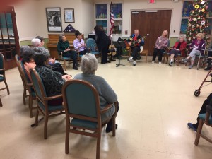 A large circle of participants sing along with talented volunteer musicians. 